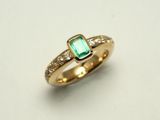 Ring aus Gelbgold 750. Mittig ist ein Smaragd gefasst in der Ringschiene ist verziert mit Brillanten.